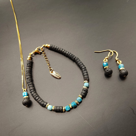 A jewelry set featuring a black and blue beaded bracelet, a necklace with a similar color scheme, and a pair of earrings with black lava stones and gold accents.